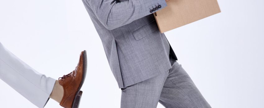 Giving him the boot. Shot of a young businessman being kicked out of his job