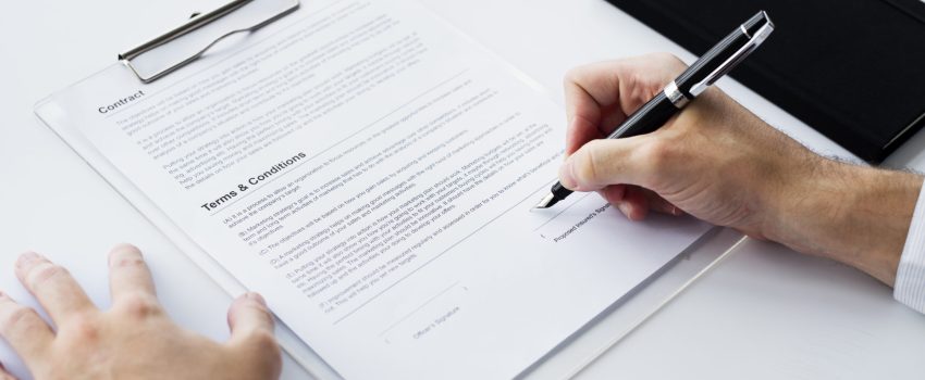 Closeup of hand signing paper workspace