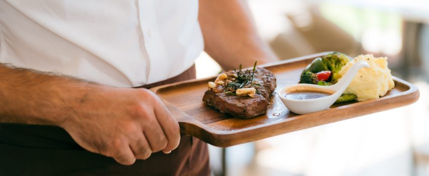 Waitress man serving food to group of diverse customer in restaurant, eatery client woman and man having smile and happy with service mind from cafes staff, lunch or dinner time lifestyle with family